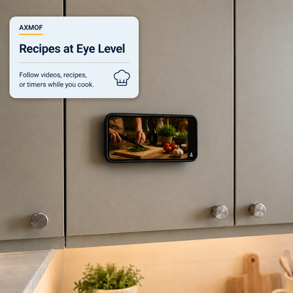 A smart kitchen display mounted on taupe cabinets shows a cooking scene on a phone screen, with a white AXMOF promotional card reading 'Recipes at Eye Level' in the upper left.